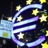 A woman holds a sign in front of the Euro currency sign next to the European Central Bank headquarters during a demonstration against the Euro Finance Week in Frankfurt